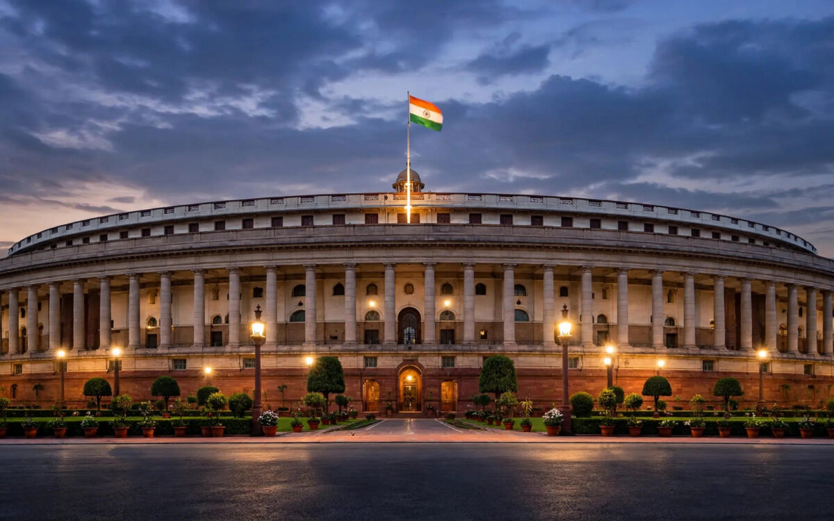 The Indian Parliament building in New Delhi at dusk with the flag flying.