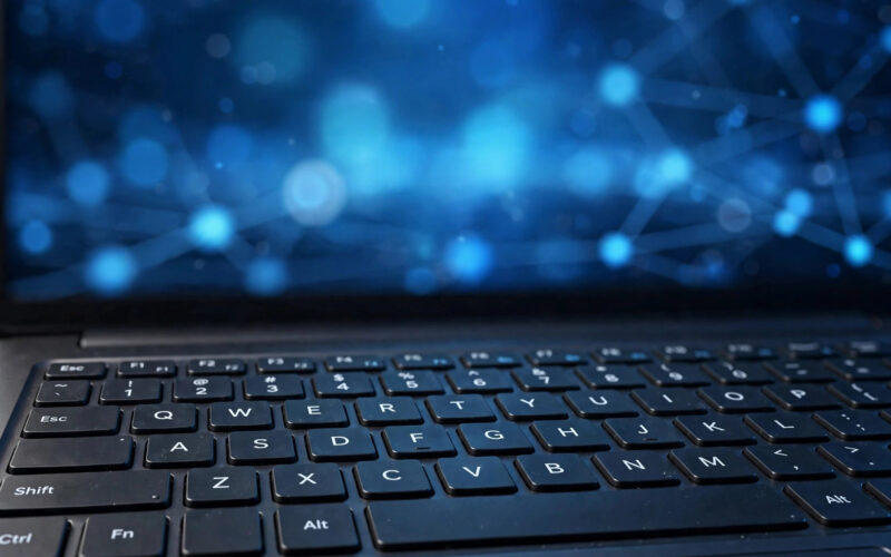 A laptop showing a generic government services website interface on a desk, with blurred abstract digital code patterns in the background.