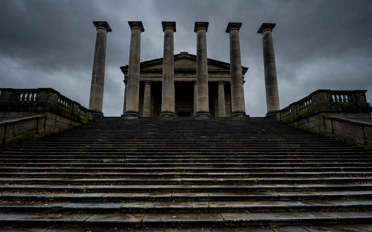 Tall stone courthouse columns silhouetted at dusk under a heavy grey sky.