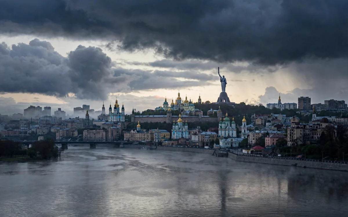 Kyiv city skyline under a dark, cloudy sky at dawn