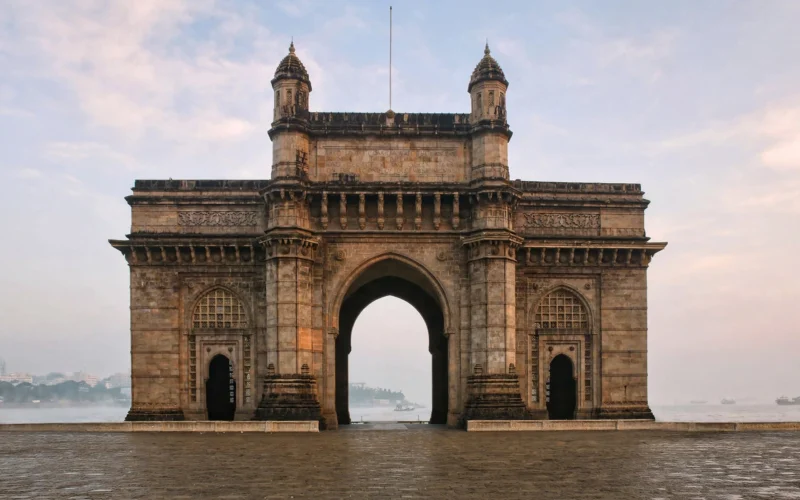 Gateway of India monument in Mumbai at dawn with the empty waterfront plaza in front.