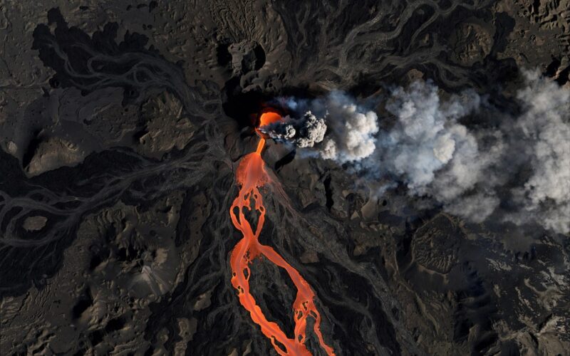 Smoking volcano seen from space with lava flow