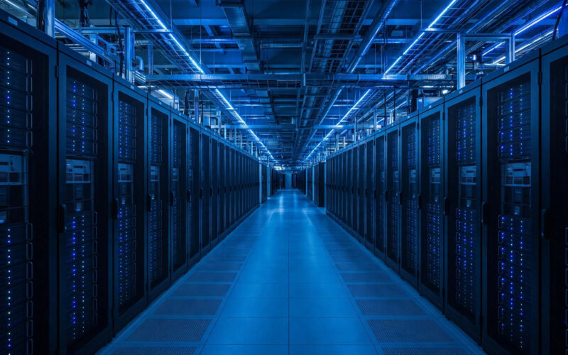 A large AI data center hall with rows of server cabinets under cool lighting.