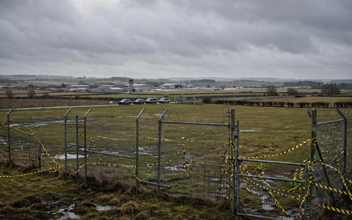 RAF Fairford air base perimeter under police cordon with emergency vehicles in distance
