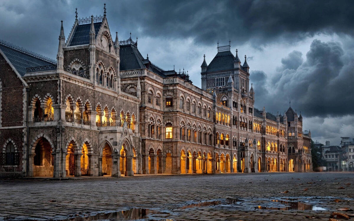 A stock exchange building at dusk under dark gathering clouds with an empty street in front.