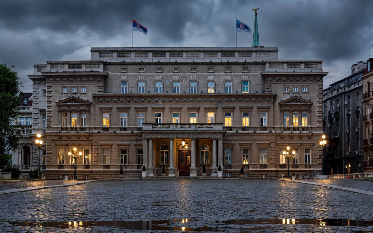 A presidential palace facade in Belgrade at dusk under moody clouds, ahead of Serbia's snap elections.